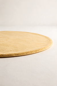 a butter yellow rug shown from a low angle, detailing the plush pile height and edge binding
