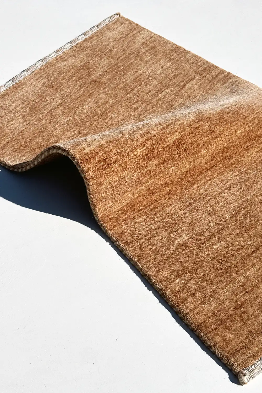 warm neutral wool rug hand-loomed and folded to show texture