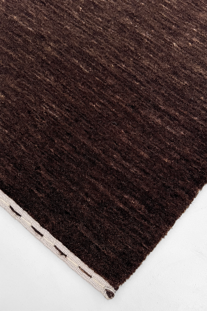 close-up texture of dark brown hand-loomed area rug 