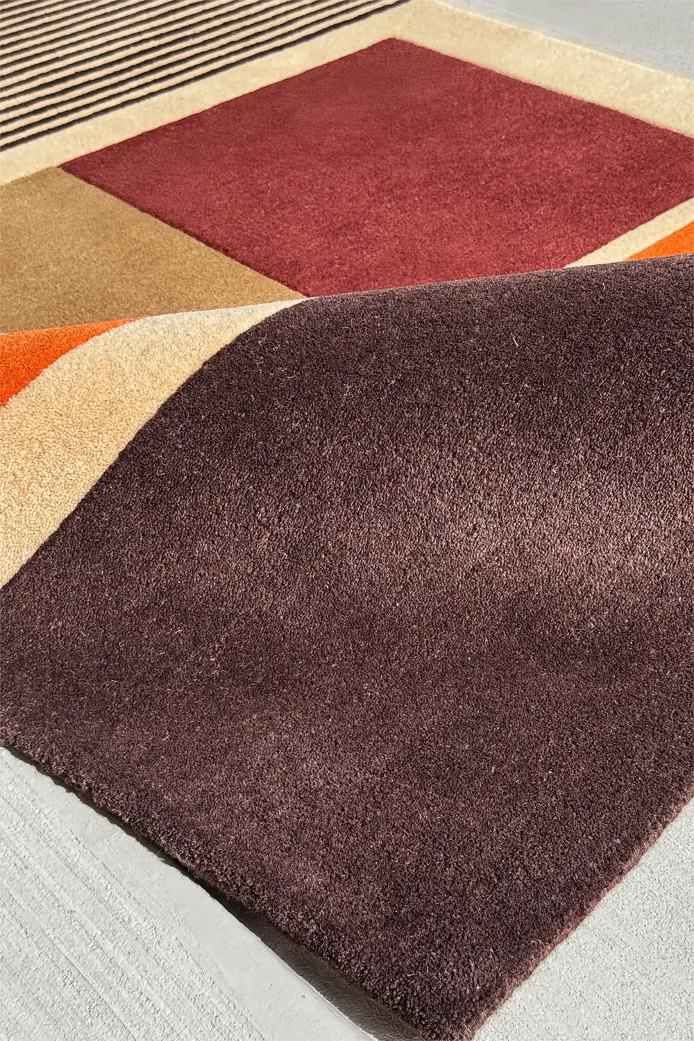 Luxury brown and red wool rug with earth-toned stripes and subtle sculpted texture