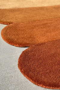 Unique scalloped edge rug in burnt orange, brown, and gold tones, perfect as a funky nursery rug