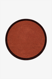 A round wool rug with a rust-orange textured center and a dark brown border, shown flat against a light gray background.