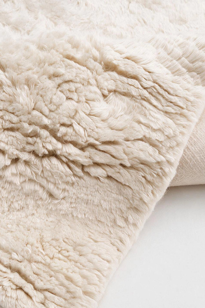 close up texture of a luxurious cream white shag area rug hand-knotted in wool