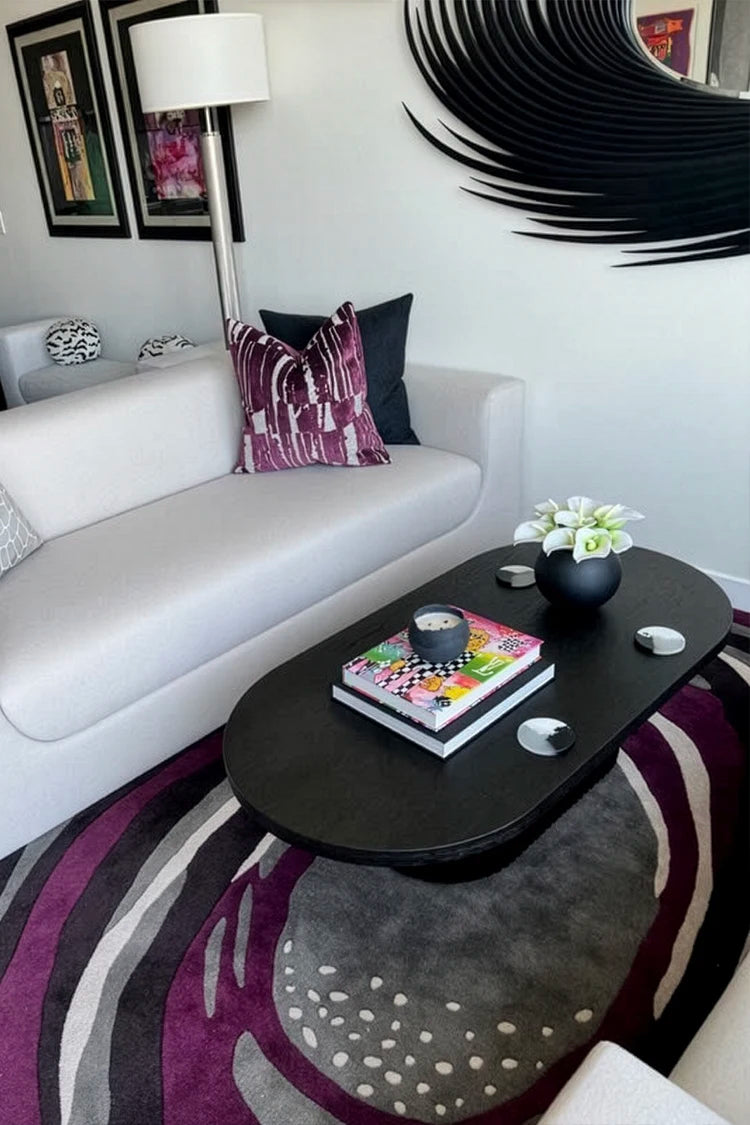 Modern living room with a large black spiral wall art piece and matching rug