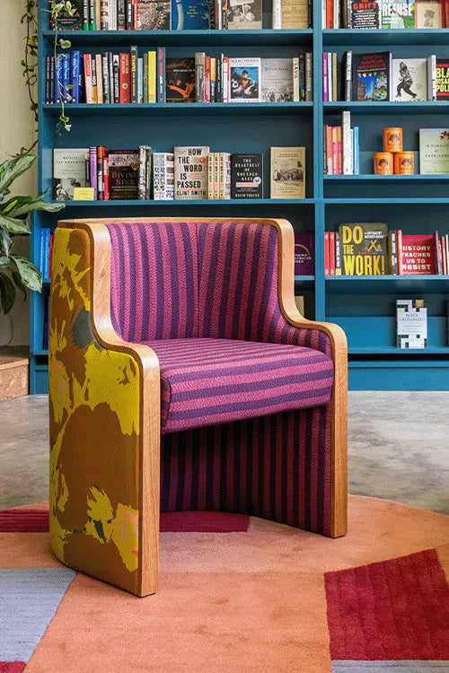 Red checkered chair in a colorful store interior with bookshelves and a patterned oval wool rug in custom colors.