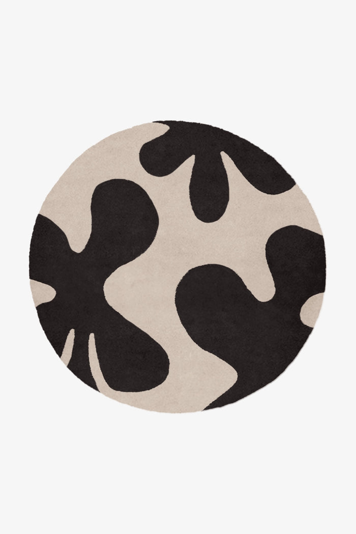 Round rug with black and beige abstract pattern on a white background