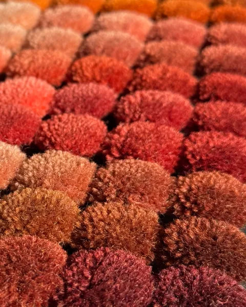 Close-up of a textured rug wool poms with red and brown colors