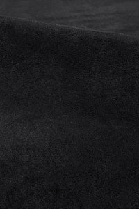 Close-up of plush black wool rug surface showing hand-tufted pile and smooth velvety texture oreo