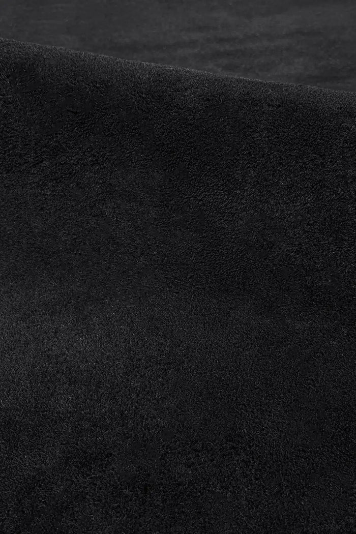 Close-up of plush black wool rug surface showing hand-tufted pile and smooth velvety texture oreo