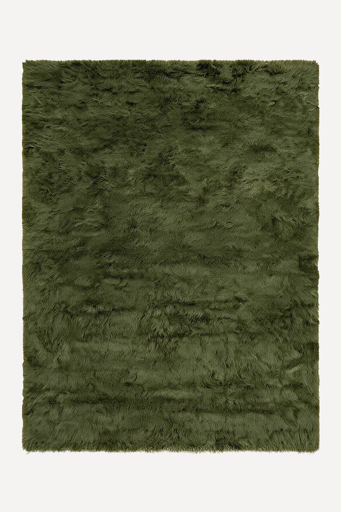 A dark olive green shaggy wool rug shown flat against a plain off-white background.