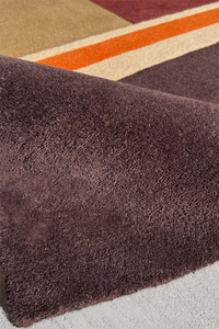 Luxury striped rug in deep brown and red tones with an earthy wool texture