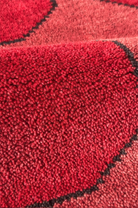 Close-up of a red runner rug texture surface with black stitching