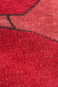 Close-up of a red textured rug with geometric pattern