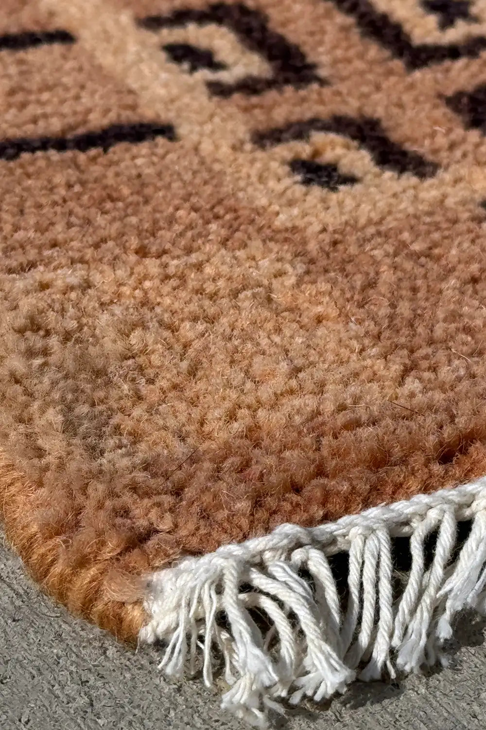Close-up of corner fringe on mid-century style wool rug, showing detailed geometric border in black and taupe