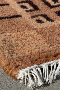 Close-up of corner fringe on mid-century style wool rug, showing detailed geometric border in black and taupe