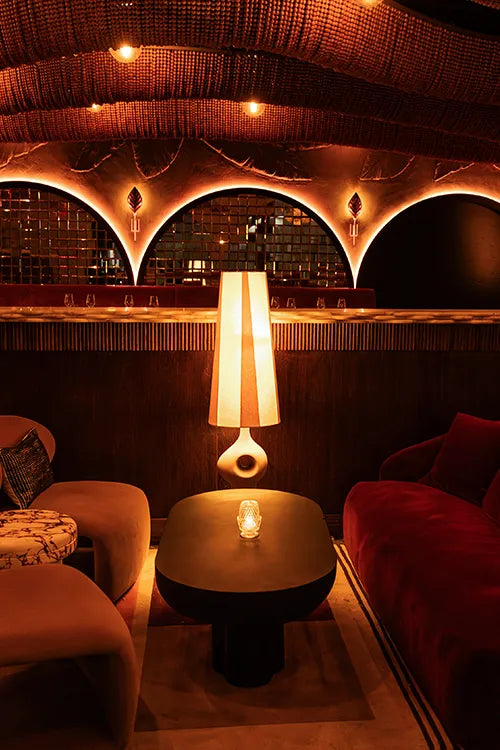 Modern lounge with brown sofas, a black coffee table, and decorative ceiling lights.