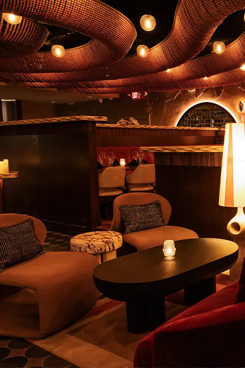 Modern lounge with brown sofas, a black coffee table, and decorative ceiling lights.