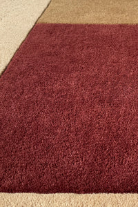 A close-up of a plush runner rug in a deep burgundy red, showing its thick texture and soft fibers.