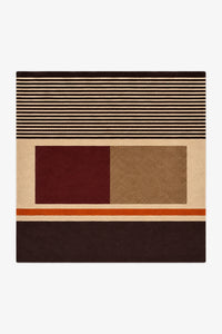 A square area rug with a modern geometric pattern featuring stripes, solid blocks, and a thin orange accent stripe, shown flat against a light gray background.
