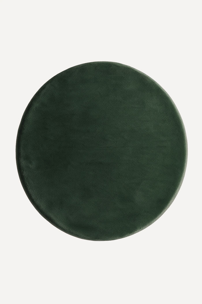 A round dark forest green wool rug shown from a top-down view on a plain off-white background.