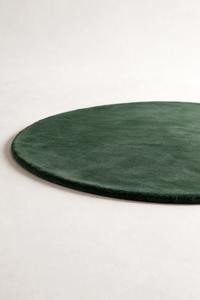 a forest green round rug on a studio floor