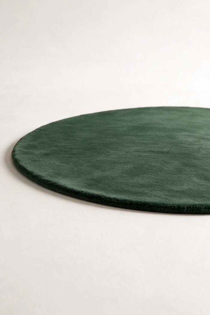 a forest green round rug on a studio floor