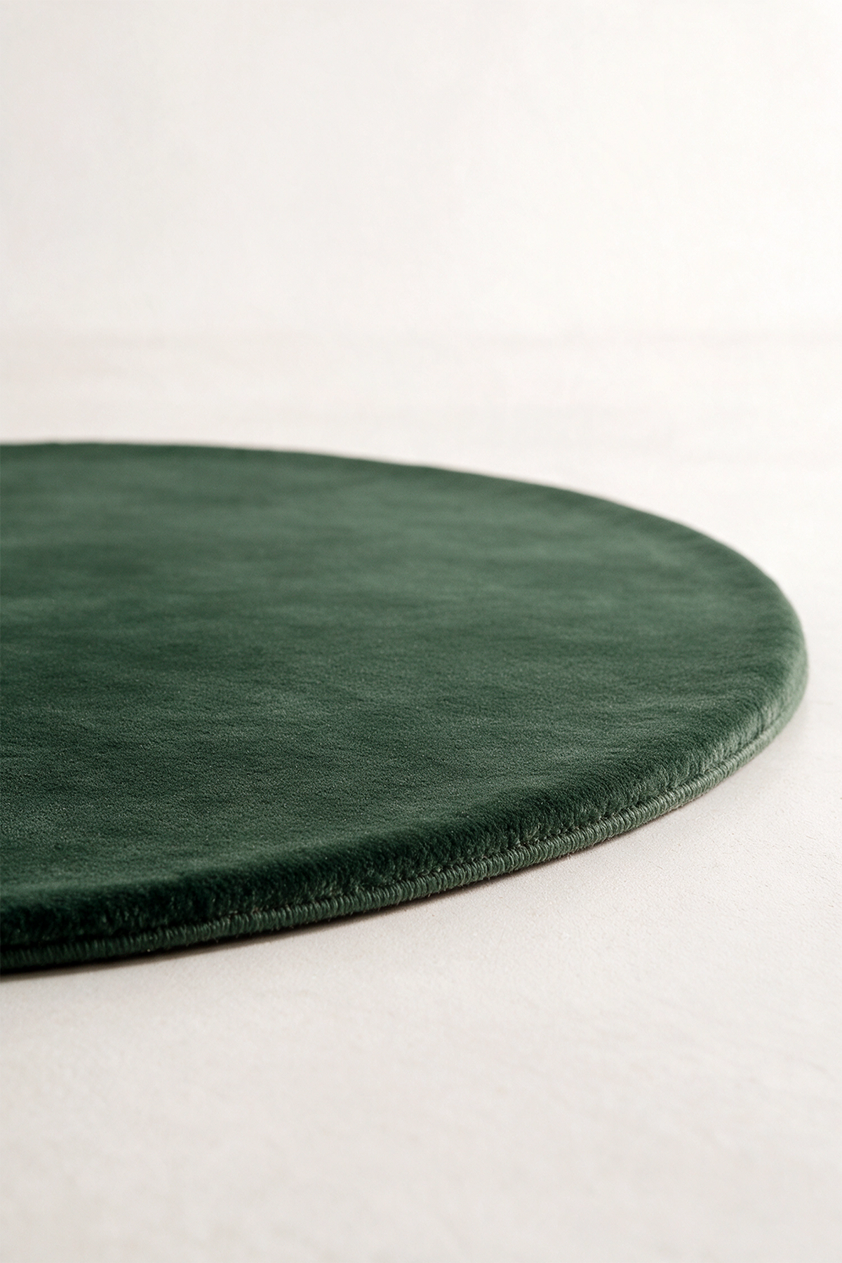 a dark forest green oval rug shown from a low angle
