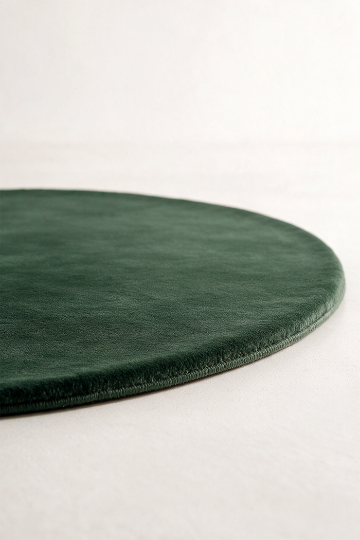 a dark forest green oval rug shown from a low angle