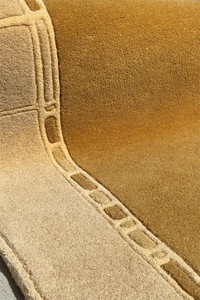 Macro detail of golden wool field and taupe geometric carving, perfect for modern irregular shaped rugs in neutral tones