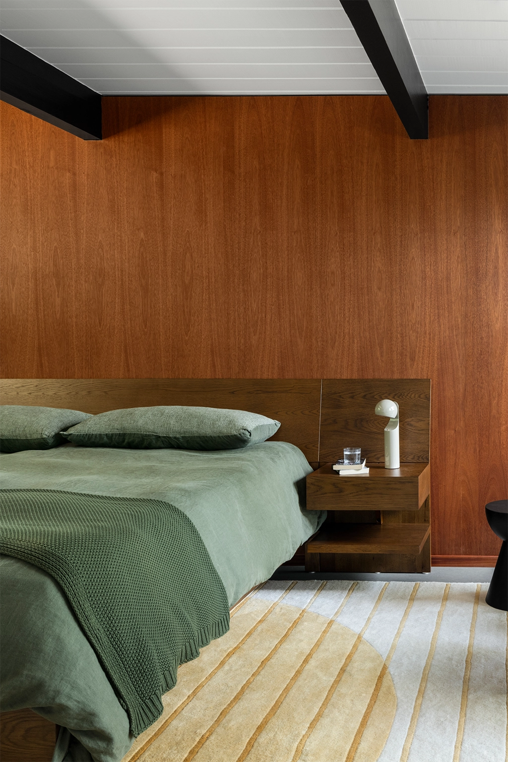 Modern bedroom with wooden headboard and gold striped mid century rug lifestyle | Marshall Interiors