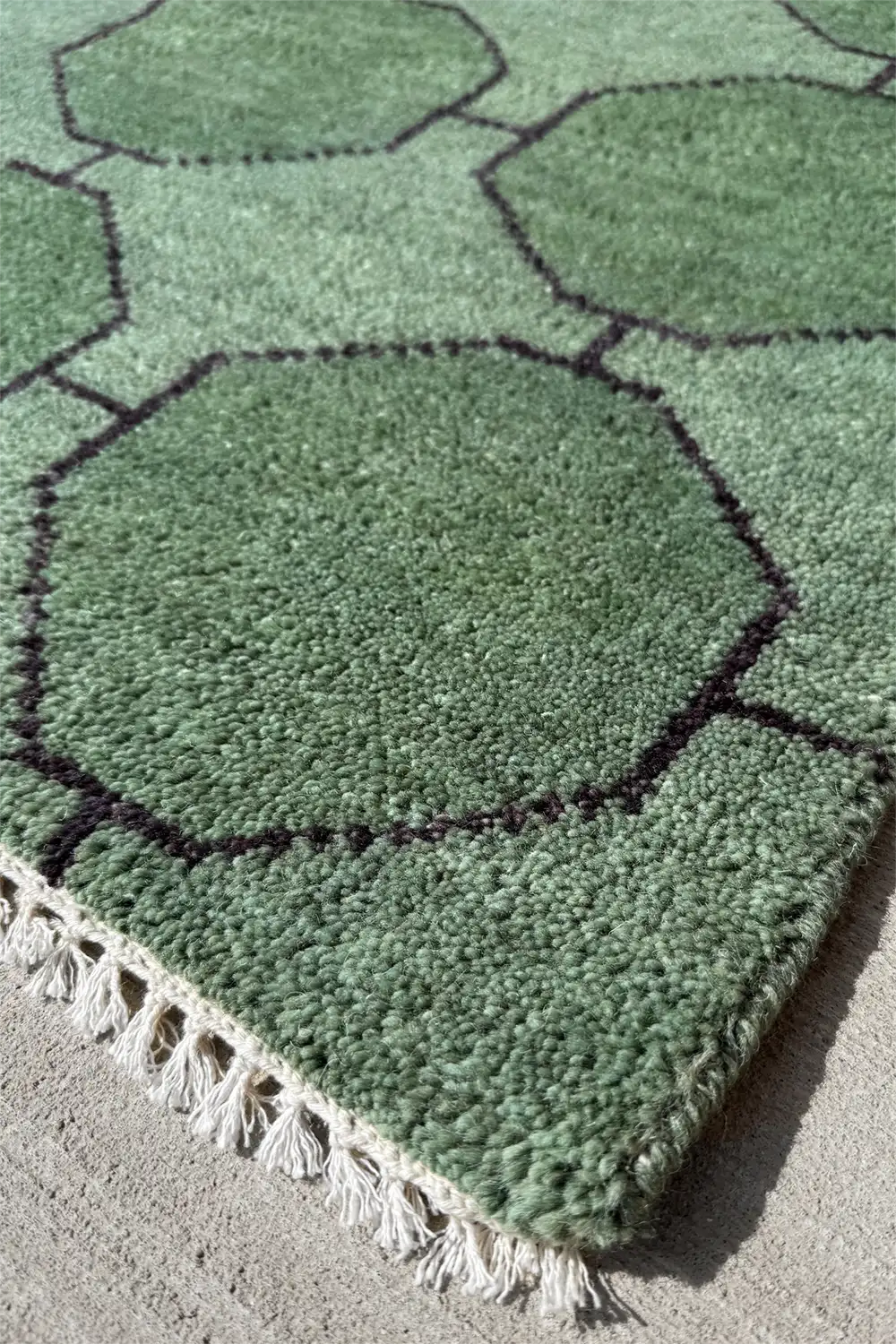 Hand-knotted green wool rug with geometric octagon pattern and fringe detail