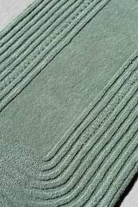 Raised line detail on soft sage green tufted wool rug, a zen garden-inspired piece perfect for Japandi or boho interiors