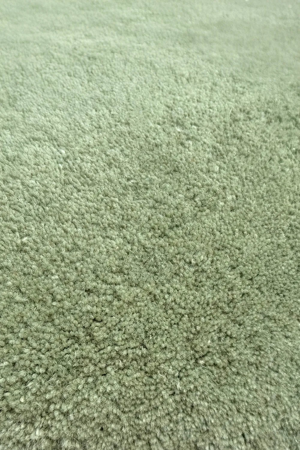 Soft sage green wool square rug surface shown close up, emphasizing plush hand-tufted quality for fun and functional playroom rugs