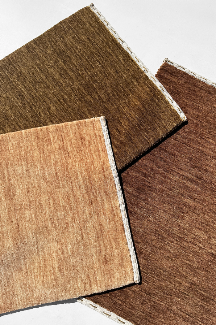three earth toned loomed rugs laid on top of each other | Haven in Hazel, Camel, and Chestnut
