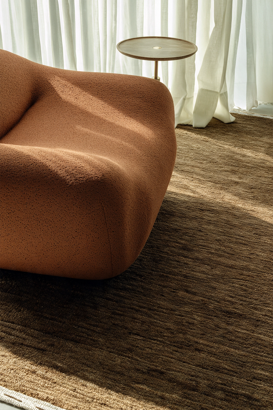 a modern seating area with a hazel green olive loomed textured rug and a thick terracotta chair lifestyle