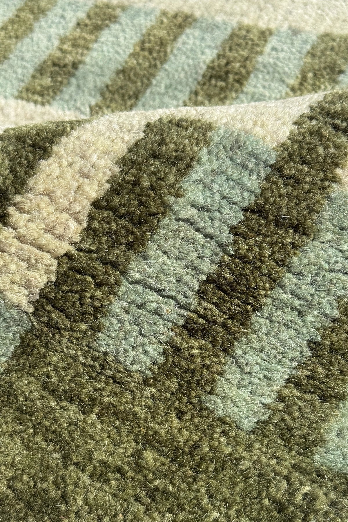 Close-up of a textured woven rug with a striped pattern in olive green and sage