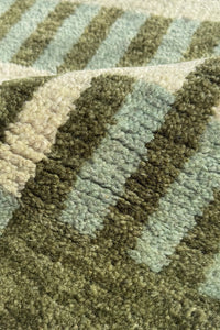 Close-up of a textured woven rug with a striped pattern in olive green and sage