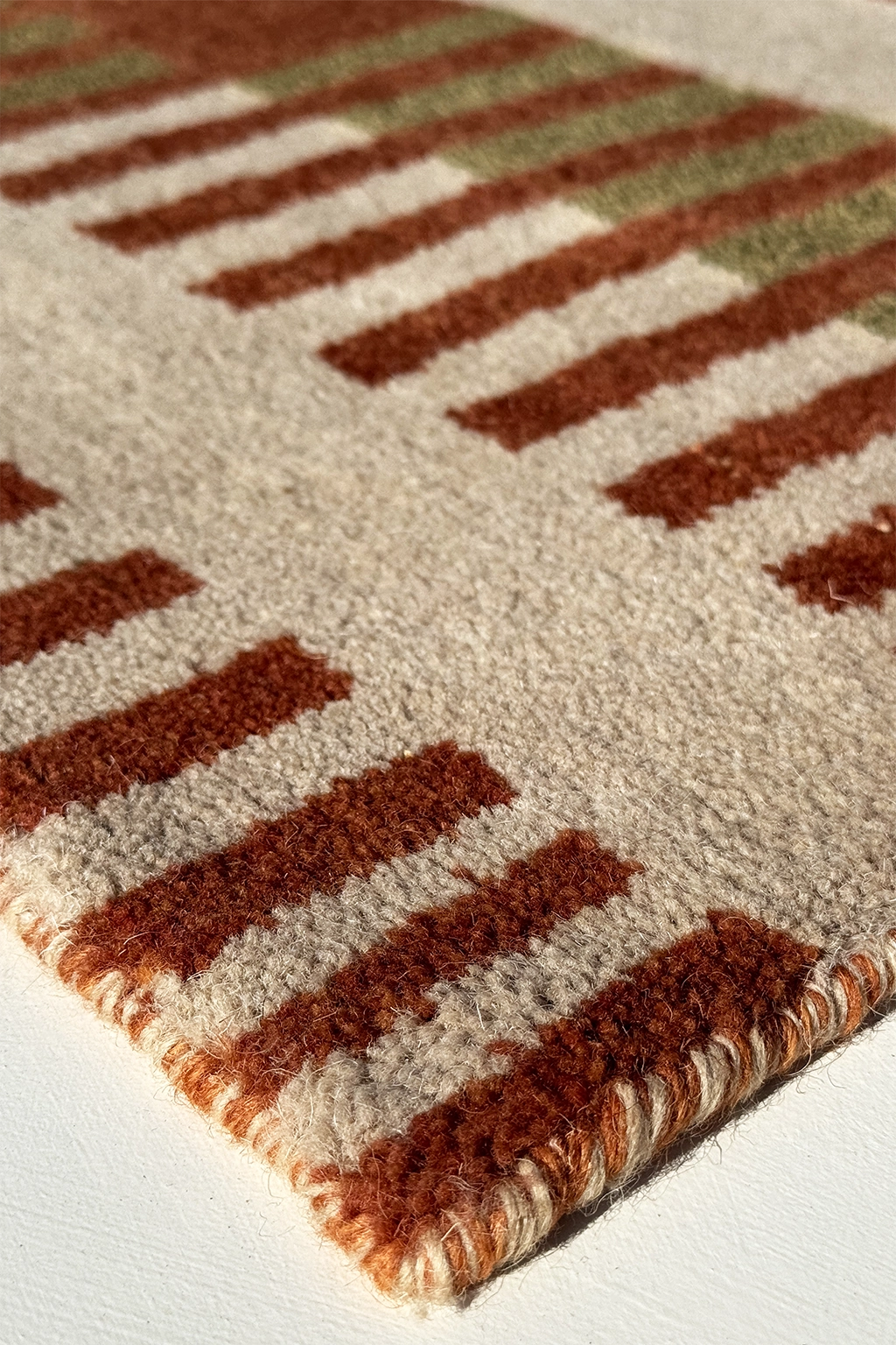 hand-knotted wool pile of a modern square rug in rust and tan multicolor