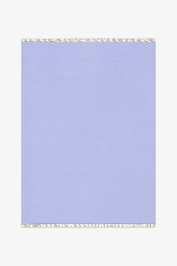 Light blue rug with white fringe on a white background