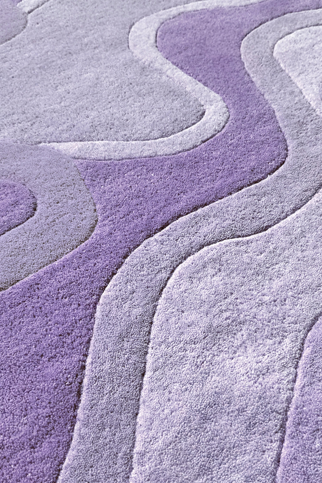 A close-up of a textured area rug with a wavy, layered pattern in shades of lavender purple and light gray.