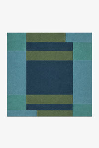 square rug with a geometric pattern of blue and green squares on a white background