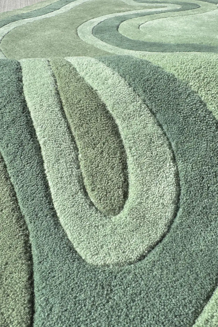 Close-up of sage green sculpted wool rug texture, showing carved organic pattern and plush surface detail for a cozy boho space