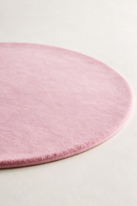a pink round rug with soft texture shown from a low angle