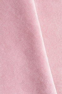 A close-up of soft light pink wool rug with a smooth, slightly velvety texture and a diagonal fold running through the center.
