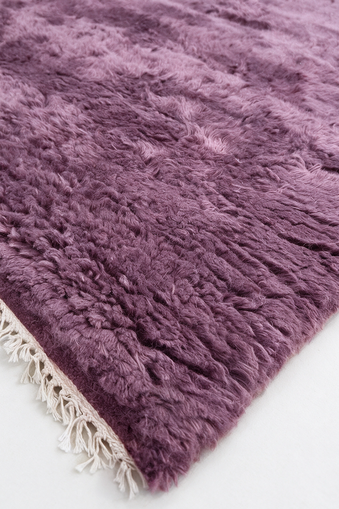 close up texture of a soft shaggy mauve purple rug