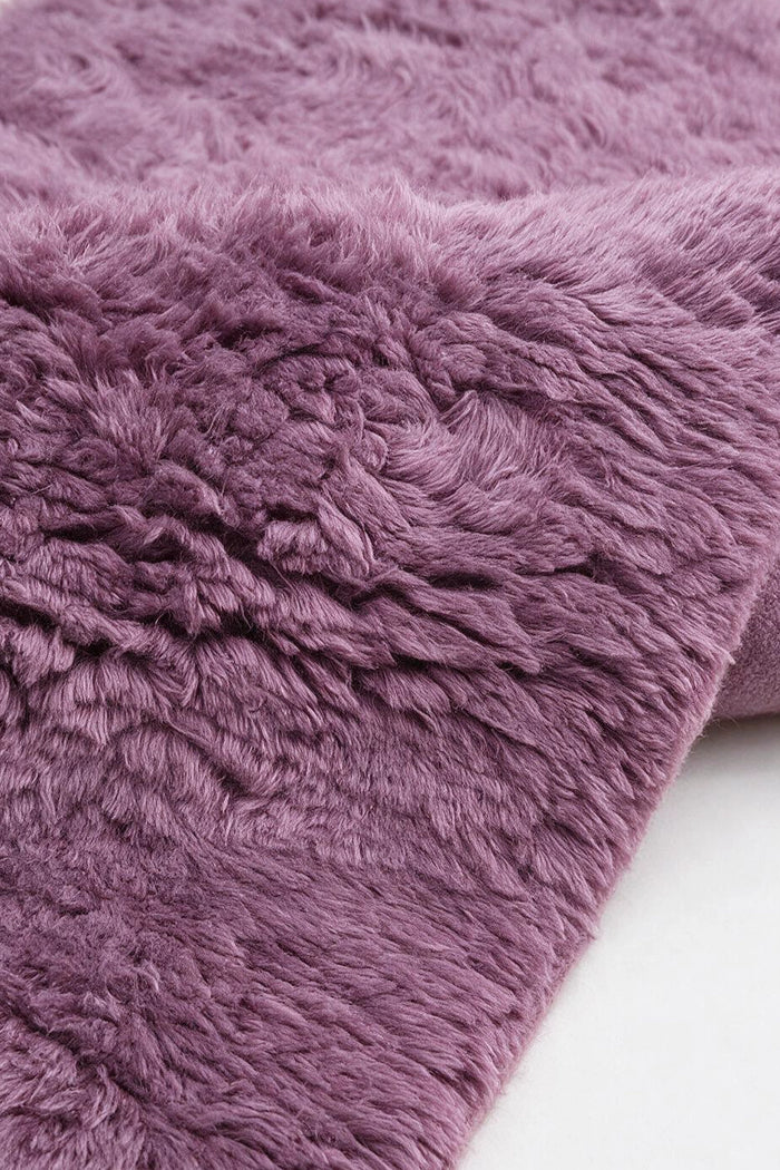 close up pile of a mauve purple shaggy rug with soft texture