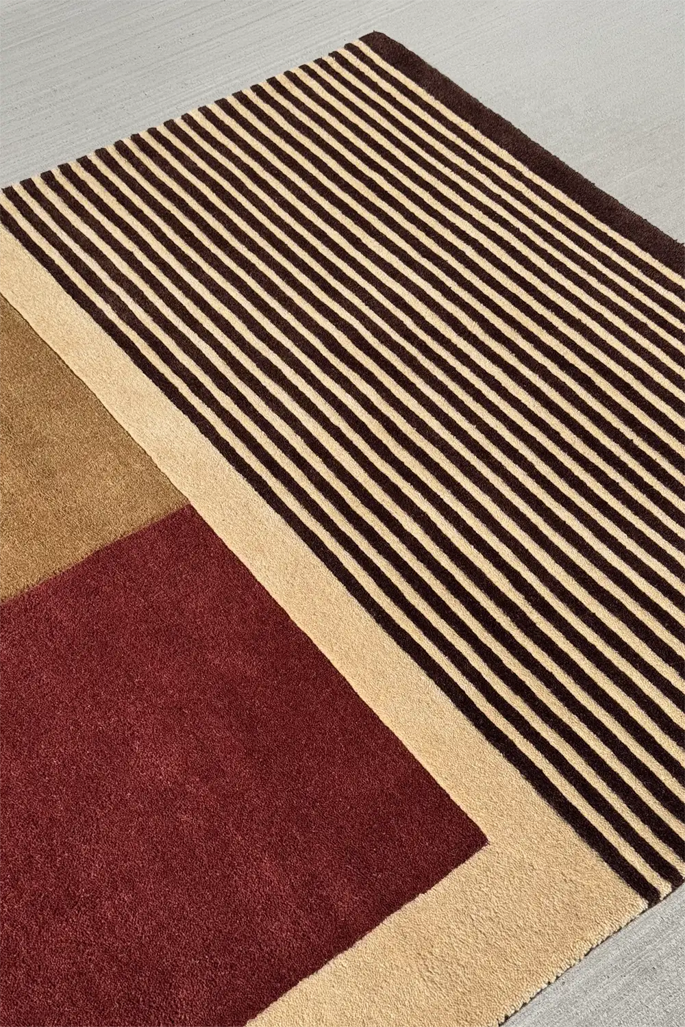 Neutral wool area rug in 4x6 with midcentury color blocking in burgundy, tan, and black
