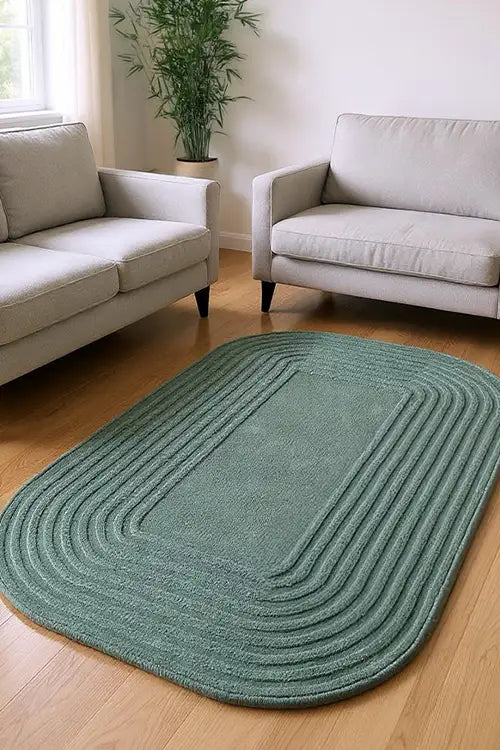 oval sage green rug on a wooden floor in a living room with beige sofas.