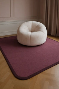 Dark purple wool rug with rounded edges, creating a soft modern foundation for a minimalist living room lifestyle