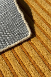 Close-up of a striped textured wool hand-tufted rug with cotton backing and finished edges